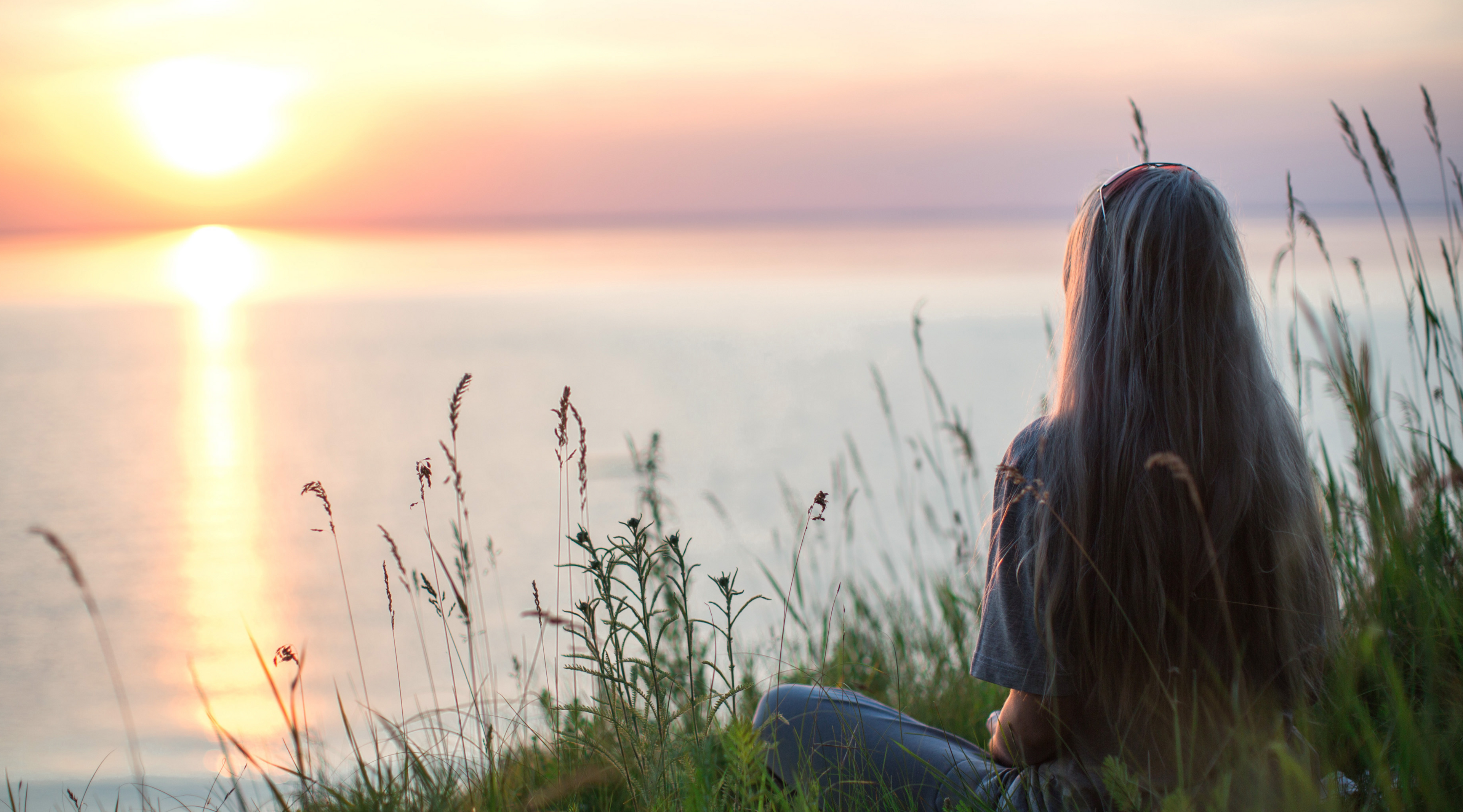 Sitting women gazing over sunset lake